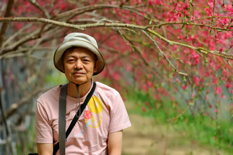 【桃花廊靠鐵桿撐起出乎意料,遠攝近拍費心截取最佳樣貌。背景的深紅是蟠桃花。】