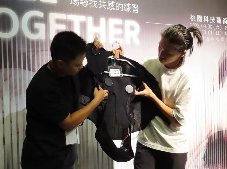 技術團隊於活動前記者會介紹「共感背心」穿戴裝置。圖片來源：工商時報。