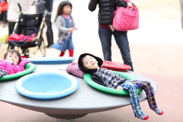 肢體不便身障童躺靠著玩多人旋轉杯。〔新竹中央公園〕